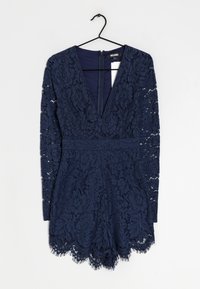 Granatowa sukienka koronkowa z długimi rękawami, głębokim dekoltem w kształcie litery V, kwiatowymi wzorami i falbanistym dołem. Zapinana na zamek z tyłu.