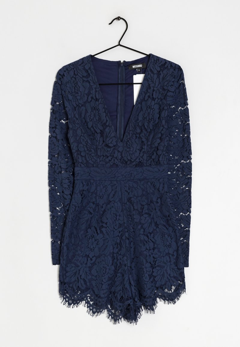 Granatowa sukienka koronkowa z długimi rękawami, głębokim dekoltem w kształcie litery V, kwiatowymi wzorami i falbanistym dołem. Zapinana na zamek z tyłu.