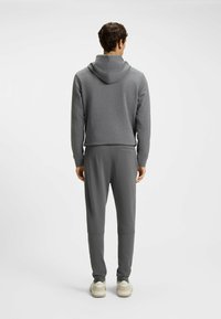 Gray hooded sweatshirt paired with matching joggers, featuring a soft texture and a fitted design. White sneakers complete the look.