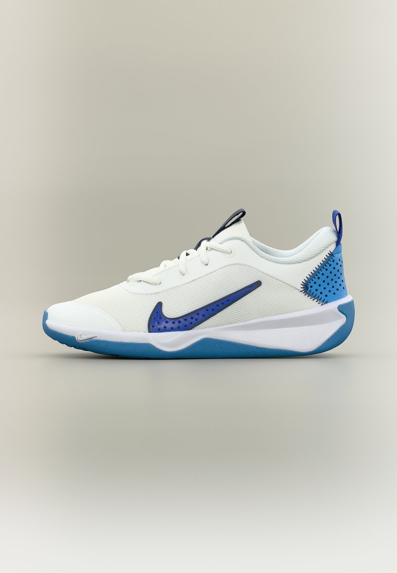 Weißer Sportschuh mit blauer Sohle, blauem Nike-Swoosh mit Punkten, blauer Fersenstütze und weißen Schnürsenkeln vor neutralem Hintergrund.