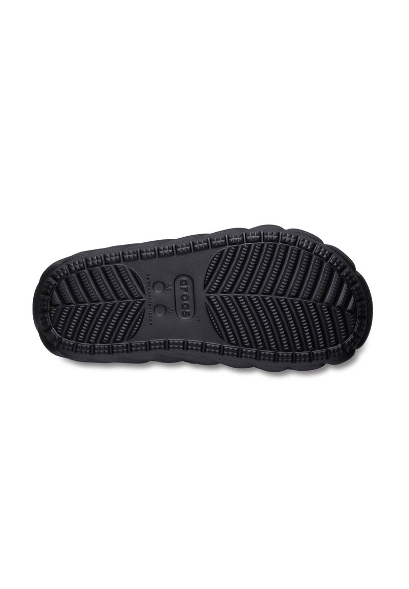 Zwarte rubberen schoenen zool met een gestructureerd profiel, voorzien van groeven en verhoogde accenten; er is een cirkelvormig logo en merkdetails aanwezig.