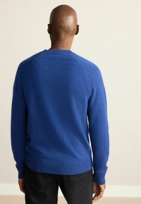 Blauer Strickpullover mit geripptem Saum und Bündchen. Verfügt über eine weiche Textur und Raglanärmel. Rückansicht mit rundem Halsausschnitt.