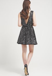 Černé mini šaty se sektory, hlubokým výstřihem na zádech a elastickým pasem. Obsahují volánkovou sukni, vertikální pruhovanou vzor a tenké ramínka.