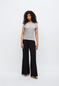 Γκρι πλεκτό τοπ με κοντά μανίκια και στρογγυλή λαιμόκοψη, συνδυασμένο με μαύρο παντελόνι φαρδιάς γραμμής. Το σύνολο έχει άνετη εφαρμογή και μαλακή υφή.