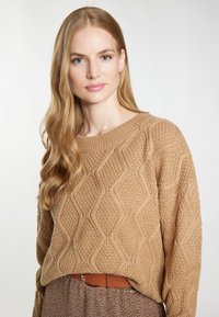 Sweter dziany w jasnobrązowym kolorze z teksturowanymi diamentowymi wzorami, z długimi rękawami i okrągłym dekoltem.