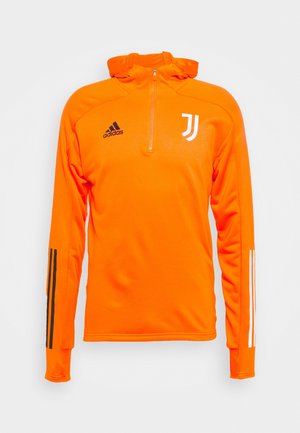 Haut de sport manches longues orange vif avec une demi-fermeture éclair à l'avant, logo Adidas noir sur la poitrine droite, logo Juventus blanc sur la gauche et manches rayées.