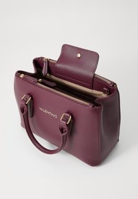 Burgundy leather handbag with gold hardware, top zip closure, and a front flap. Features double handles and an interior zip pocket.