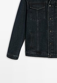 Dunkelblaue Jeansjacke mit Metallknöpfen, Brustklappentasche und vertikalen Seitentaschen, linke Ärmel und Vorderteil sichtbar.