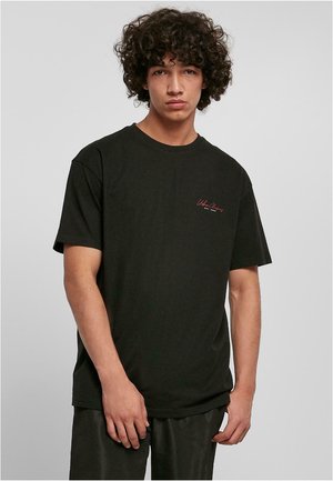 T-shirt noir à manches courtes avec col rond, en coton doux. Présente un petit logo en texte rouge sur la zone de la poitrine gauche.