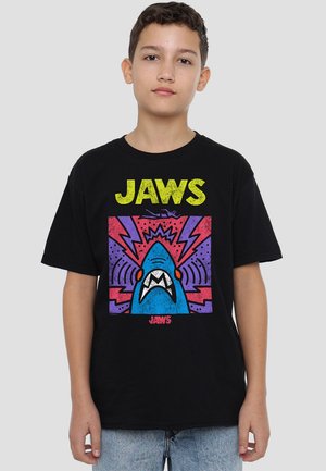 Black cotton T-shirt featuring a graphic print of a blue shark with red accents, surrounded by colorful lightning bolts and "JAWS" text.
