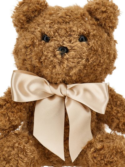 Un ours en peluche brun et moelleux avec un extérieur en fourrure texturée et des yeux en plastique noirs. Il est orné d'un grand nœud en satin crème autour de son cou.