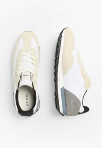 Beige und weiße Sneaker aus einer Mischung aus Wildleder und Textilmaterialien. Sie verfügen über eine schwarze Sohle, graue Akzente und ein Schnürdesign.