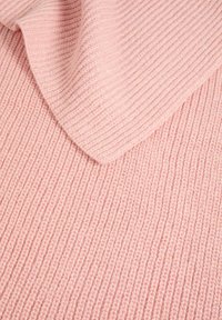 Tessuto lavorato a maglia in un morbido rosa, con una texture a coste. Il design presenta una finitura liscia e si drappeggia delicatamente con un bordo piegato.