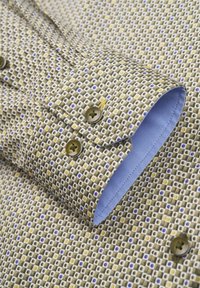 Musterhemd mit kleinen quadratischen Motiven in Braun, Gelb und Blau; kontrastierende blaue Innencuff; runder Kragen; zwei runde Knöpfe.