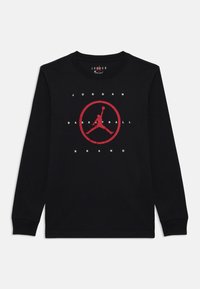 Melna garā piedurkne T-kreklu, kas izgatavots no kokvilnas, ar centrālo sarkano Air Jordan logotipu un uzrakstu "JORDAN BASKETBALL BRAND". Klasisks apaļas kakla dizains.