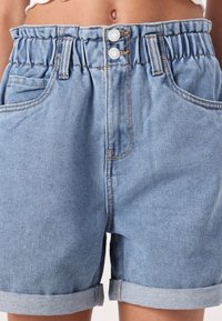 Ljust blå denimshorts med hög midja och elastik, två framfickor, uppvikta fållar och synliga sömmar.