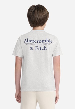 Camiseta de algodón gris con mangas cortas, que presenta texto azul en la parte trasera que dice "Abercrombie & Fitch" y un aviso de marca registrada debajo.