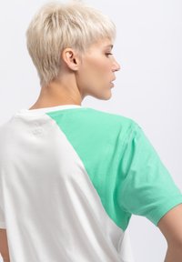 Korte mouwen t-shirt met een witte lijf en aqua groene accenten op de schouders en mouwen, gemaakt van zacht katoen met een gladde textuur.
