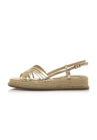 Goldene Sandalen mit Riemen und einer geflochtenen Jute-Plattformsohle, ausgestattet mit glänzenden metallischen Riemen, verstellbarem Knöchelverschluss und flachem Fußbett.