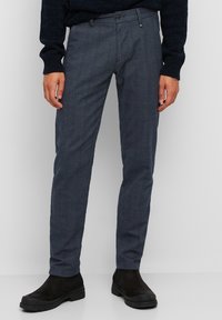 Pantaloni a quadri grigio scuro realizzati in tessuto leggero, con vestibilità slim, tasche frontali e chiusura con bottone, abbinati a stivaletti neri alla caviglia.