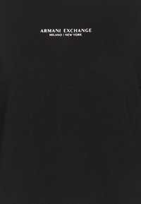 Svart bomullströja med rund halsringning. Texten "ARMANI EXCHANGE MILANO / NEW YORK" tryckt i vitt på framsidan. Sllät textur.