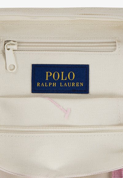 Plátená taška s bielym telom, so námorníckom modrým štítkom so zlatým textom "POLO RALPH LAUREN" a ružovou vyšitou akcentou. Obsahuje zipsové uzatvorenie.