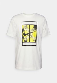 Camiseta de algodón blanca con un gran diseño gráfico enmarcado en negro y elementos amarillos, con el logo de Nike centrado dentro de un marco rectangular.