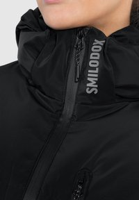 Giacca imbottita nera con collo alto, chiusura con zip e logo sulla spalla. Tessuto liscio con tasche funzionali con zip.