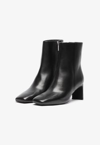 Μαύρες δερμάτινες μπότες μέχρι τον αστράγαλο με τετράγωνη μύτη, πλαϊνό φερμουάρ και ταπεινό τετράγωνο τακούνι. Λείο υλικό με κομψό σχέδιο.