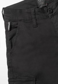 Zwarte broek van een gladde stof, met een traditionele tailleband, voorzakken en subtiele stikdetails.