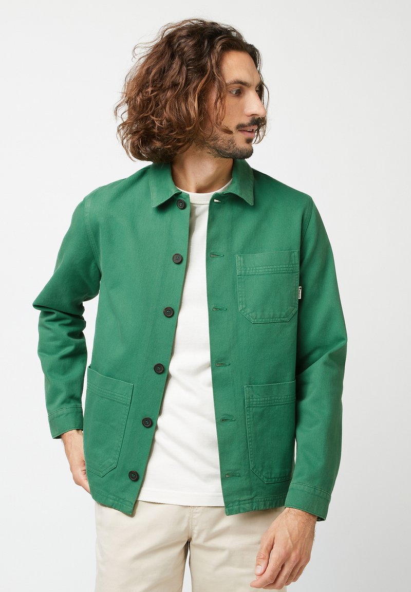 Groene katoenen jas met een kraag, knoopsluiting aan de voorkant, twee opgestikte zakken en een klein merklabel op de zak.