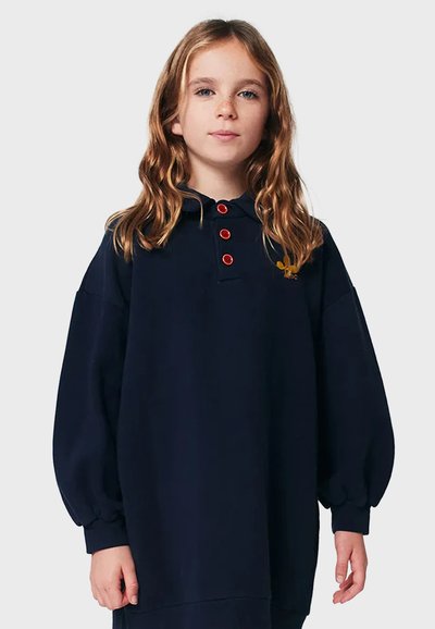Námornícka modrá oversized mikina s kapucňou, červenými gombíkmi a zlatým logom. Má balónové rukávy a textúrované manžety.