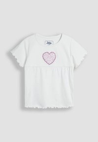 Camiseta blanca de manga corta con mangas rizadas, que presenta un diseño de corazón rosa en el pecho y una etiqueta de logo cosida directamente.