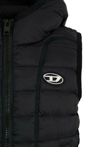 Gilet imbottito nero con zip frontale, dotato di pannelli testurizzati, cappuccio e una patch logo bianca. Materiale liscio con dettagli cuciti.