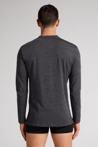 Dlouhý rukáv košile z tmavě šedé látky, lehká s jemnou texturou. Má kulatý výstřih a rovný lem, minimalistický design.