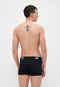 Svarta boxerkalsonger med en bred, elastisk midjeband som har vita logodetaljer. Slät textur, åtsittande design och längd till mitten av låren.