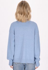 Maglione oversized blu chiaro con polsini e orlo a costine, dalla texture morbida, spalle scese, caratterizzato da un design posteriore semplice senza decorazioni visibili.