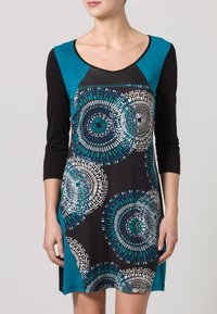 Robe noire avec des accents turquoise, dotée d'un col rond et de manches trois-quarts. Motifs circulaires géométriques en bleu et blanc.