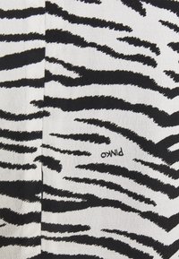 Tessuto bianco e nero con un motivo a strisce zebra. Il materiale presenta una finitura testurizzata con cuciture visibili e un'etichetta vicino al fondo.