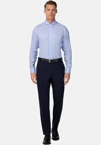 Svetlomodrá károvaná košeľa s dlhými rukávmi a golierom na gombíky, skombinovaná s tmavomodrými oblekovými nohavicami a čiernym opaskom, nosená s čiernymi topánkami.