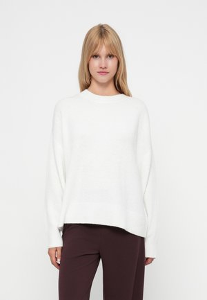 Pull en tricot blanc, surdimensionné, avec un col ras du cou, des épaules tombantes et un ourlet côtelé. Texture douce et coupe ample.