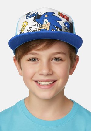 Smiling young boy wearing a blue Sonic the Hedgehog cap and a light blue shirt, facing forward against a plain background.