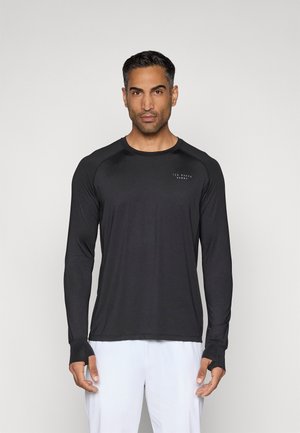 Långärmad svart sporttröja med rund halsringning, tumhål på ärmarna och en liten logotyp på bröstet. Mjuk, stretchig tyg.