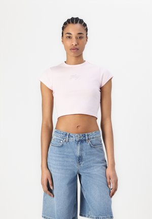 Light pink cropped t-shirt with short sleeves and embroidered logo, paired with light blue knee-length denim shorts. Smooth texture.