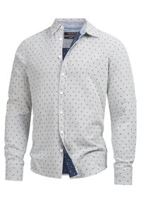 Camisa de manga larga abotonada en tela gris claro con pequeños patrones geométricos en azul marino, con cuello y un corte clásico.