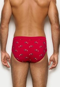 Czerwone bawełniane slipy o dopasowanym kroju, z wesołym wzorem postaci z kreskówek w różnych kolorach. Elastyczny pas.