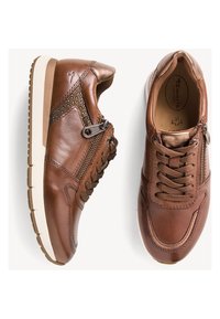 Baskets en cuir marron avec une finition lisse, dotées de lacets et de fermetures éclair, avec des accents texturés et une semelle en caoutchouc blanche.