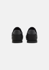 Sorte lædersneakers med en glat finish, rund tå og BOSS-logo prentet på hælen. Flad sort sål med minimale detaljer.