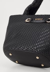 Czarna pleciona torebka wykonana ze skóry o fakturowanym wykończeniu, z akcentami w złotym kolorze i nitkami na dnie dla stabilności.