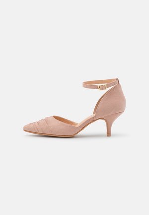 Chaussure beige en daim à talon kitten, bout pointu, détail plissé à l'avant et bride de cheville ajustable avec boucle dorée.